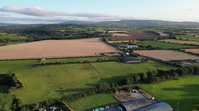 Aerial drone view of River Slaney flowing past Enniscorthy, showing winding water, patchwork farmland, village area, and rolling hills under soft morning light