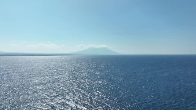 Distant view of Baluran Volcano over sea in sunny East Java, Indonesia