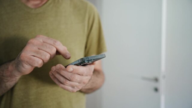 Casual man using smartphone at home close-up of hands tapping and scrolling on mobile device, 4K