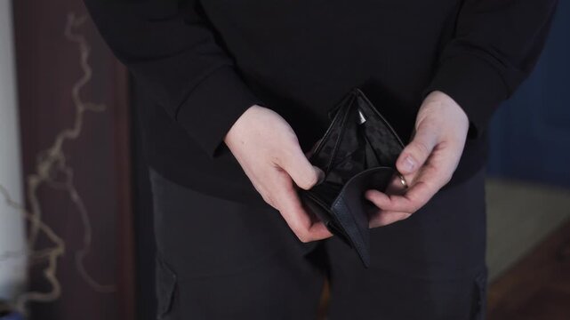 Man holding an empty wallet, showing financial hardship, bankruptcy, debt, and money shortage concept.