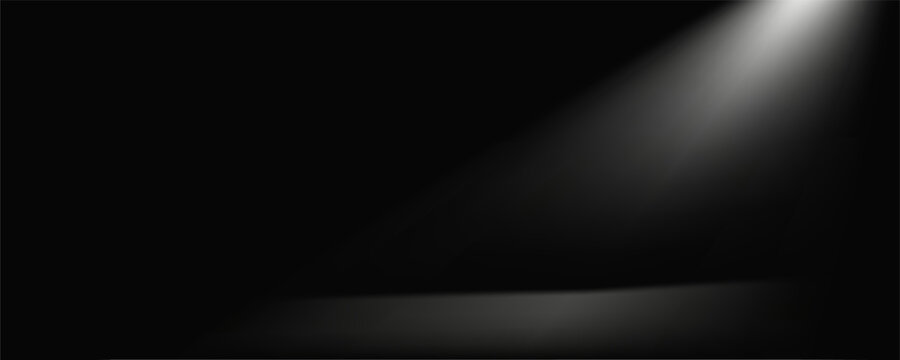 A stark, textured black surface is illuminated by a single, powerful beam of white light originating from the upper left, casting a dramatic spotlight.