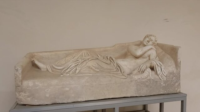 Ancient Roman marble sarcophagus featuring a beautifully carved reclining female figure in draped robes. Historic artifact displayed in a Rome museum, linked to Tivoli archaeological heritage.