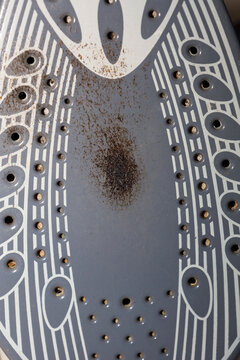 A dirty iron soleplate with visible burn marks and limescale buildup requires urgent cleaning to restore its working condition.
