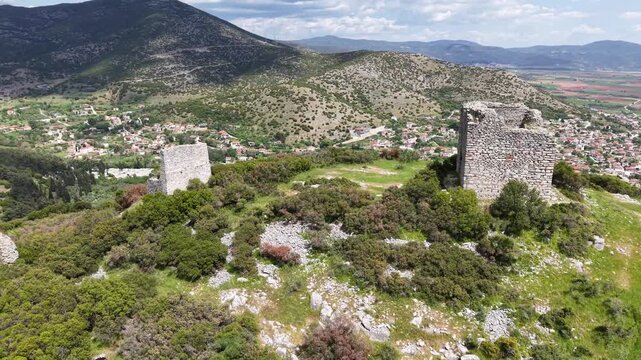 Wide drone reveal of ancient ruins within an open historic terrain.