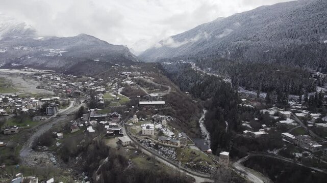 Aerial drone view of Mestia in Svaneti, Georgia with green valleys mixed with snow and high mountain peaks. Scenic landscape with traditional architecture, nature, travel, winter transition
