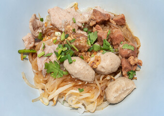 Sen Lek Haeng features delicate thin rice noodles expertly tossed in a fragrant reduction of aged soy and toasted garlic oil. This savory foundation is crowned with slow-braised pork rendered to melt- © num