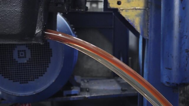 ​A close-up shot showing amber fluid draining from a heavy-duty industrial transmission unit during maintenance.