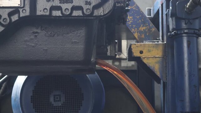 ​A close-up shot showing amber fluid draining from a heavy-duty industrial transmission unit during maintenance.