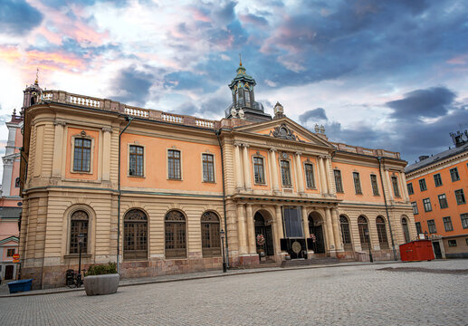 The historic Nobel Prize Museum building stands in the center of Stortorget square in Stockholm's old town under a dramatic sunset sky.