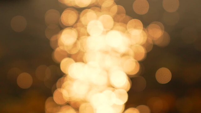 Bokeh sunlight reflection shimmering in warm golden patterns on water surfaces creating a tranquil and abstract background for creative projects