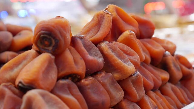 Several rows of dried persimmons arranged in pyramid formation on a public retail counter forming a compact traditional selling display. Traditional market.