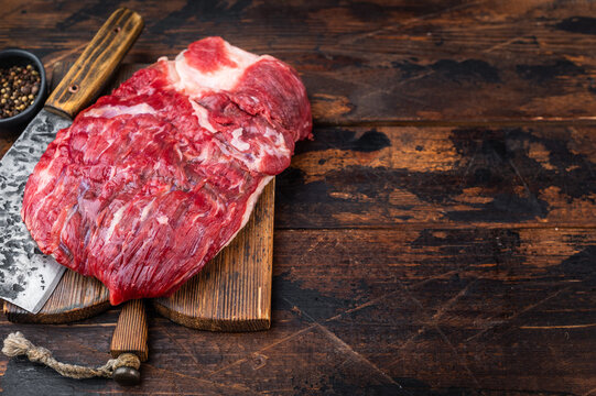 Rustic food background with raw beef brisket and cleaver, marbled meat texture and copy space for barbecue menu design
