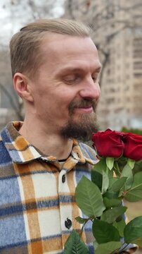 man holding gifted bouquet of roses smells flowers with pleasure. Handsome middle aged man happy with flowers received. Man and bouquet of roses. Giving flowers to men including hetero and gay.