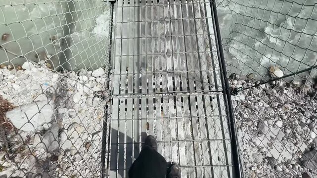 POV hiking shot, legs walking on suspension bridge over mountain river in deep gorge, Everest Base Camp trek, Nepal. Adventure trekking, high altitude travel, Himalayan landscape