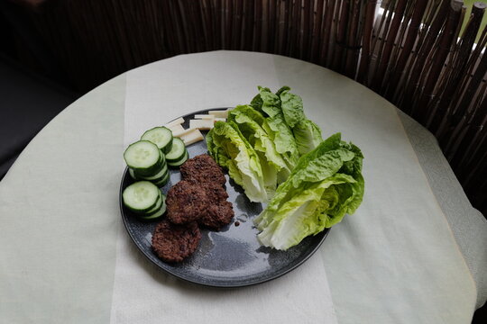 Gesundes Mittagessen: ein Teller mit Buletten, R&ouml;mersalat, Gurken und Ziegenk&auml;se.