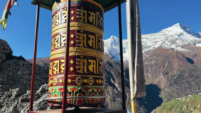 Buddhist prayer wheel spinning in Himalayas along Everest Base Camp trekking route in Nepal. Sacred Tibetan symbols with snow-capped mountain peaks in background, spiritual travel and cultural 