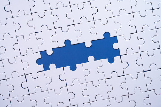 White jigsaw puzzle with missing blue pieces symbolizing incomplete solution