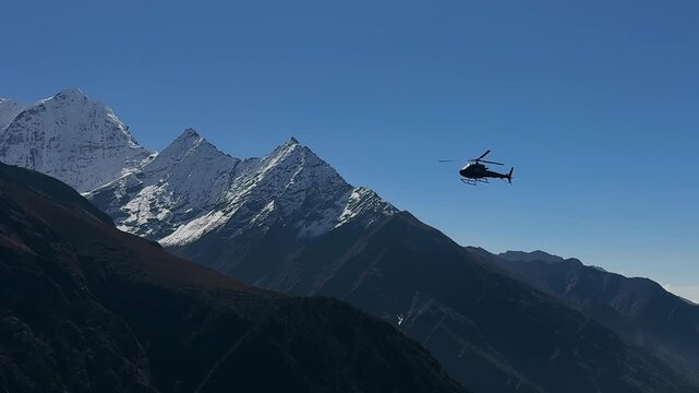 Helicopter flying over high Himalayan mountain peaks along the Everest Base Camp trekking route in Nepal. Dramatic landscapes, snow-covered summits and deep valleys, adventure travel and extreme