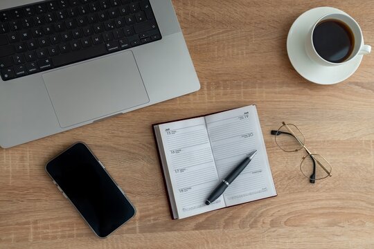 Small planner beside coffee and laptop, pen resting on open weekly spread, folded glasses and textured wood surface create calm inspired mood for idea capture and content planning