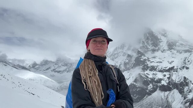 Woman taking selfie video during acclimatization hike near Dingboche on Everest Base Camp trek, Nepal. Ama Dablam and Himalayan peaks in background at high altitude, travel, adventure.