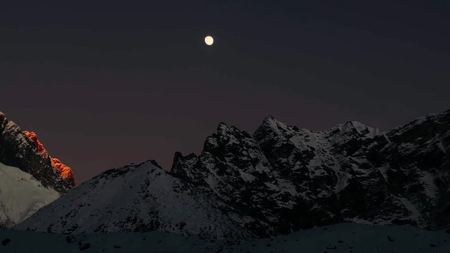 Mountain peaks at sunset with alpenglow and moonrise over Himalayas, view from Gorak Shep near Everest Base Camp, Nepal. Scenic high altitude landscape, evening sky, nature