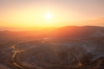 Golden Sunset Over Expansive Open-Pit Mine with Serene Mountain Views © Parilov