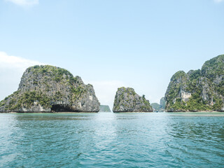 Naklejka premium Stunning views of Ha Long Bay. Symbolizes serene travel, adventure, and Vietnam's natural beauty. Ideal for tourism, vacation and scenic content. Lush greenery and calm waters create a peaceful escape
