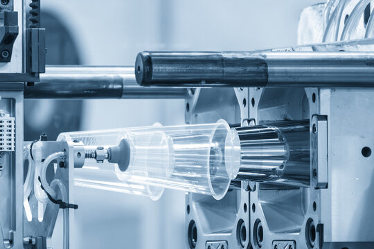 Automatic material handling process of plastic glasses from an injection molding machine in a modern factory.