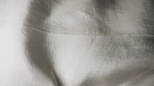 Natural silk fabric waves on wind. Abstract grey background with folds and ripples. Luxurious material flows in the air. Soft textile creates elegant moving texture.