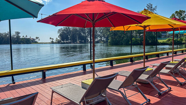 Colorful sun umbrellas and lounge chairs by waterfront, relaxing resort atmosphere, tropical vacation setting, summer отдых concept, travel and leisure background, copy space