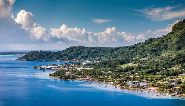 aerial landscape view along Bora Bora coastline with Vaitape, the largest city of Bora Bora Island, French Polynesia with green hilly landscape next to the village