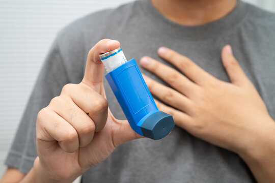 Asthma and chronic obstructive pulmonary disease COPD, Asian young man using metered dose inhaler MDI.