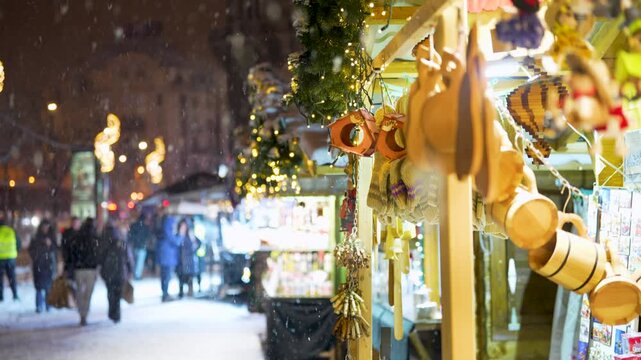 Budapest, Hungary - January 6, 2026: Handmade wooden crafts and knitted mittens hang for sale at a festive outdoor market stall in Budapest during a snowy winter night.