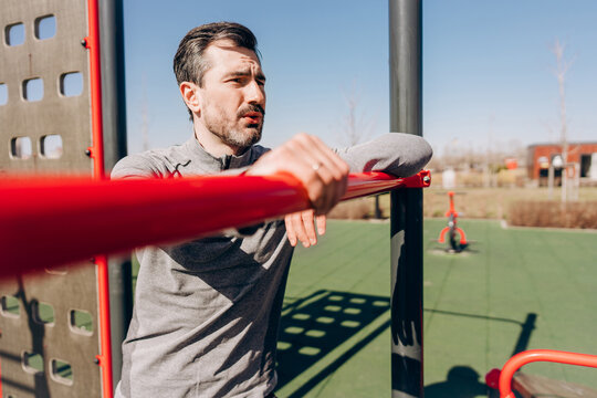 Man resting on parallel bars after outdoor workout