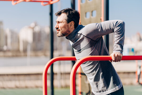 Man doing dips on parallel bars in outdoor gym