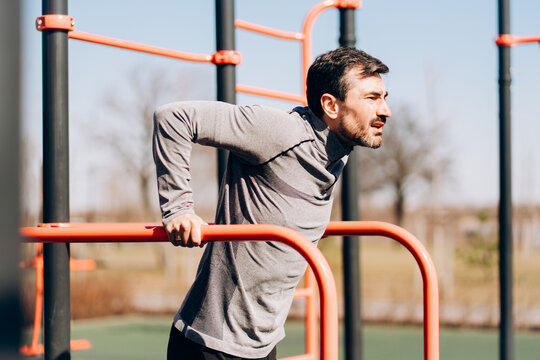 Close up man doing dips on parallel bars outdoors