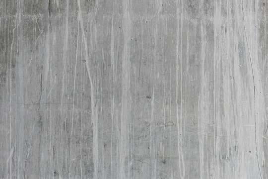 Weathered concrete wall with vertical white mineral streaks and staining texture