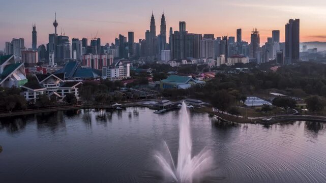 Aerial timelapse of misty morning sunrise over Kuala Lumpur city center from Titiwangsa lake park.