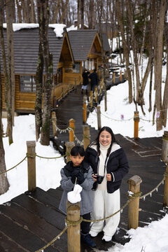 Asian mother and son travel. Traditional village. asian fat mother and family tourist Visiting in Furano, Traveler in Sweater sightseeing Ningle Terrace Cottages. landmark for attractions in Hokkaido