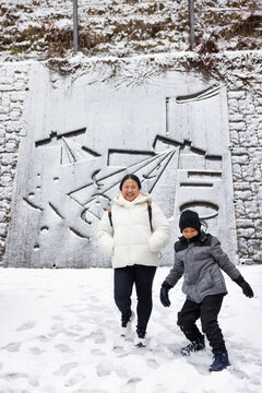 Family travel and Vacation together, Asian mother and son Traveler on Sidewalk with Cityscape Background. street. Boy Enjoying Sunny Winter Day in Picturesque Town. child posture suggests curiosity