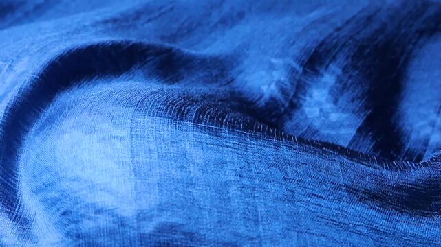 Blue silk fabric waving in the wind. Abstract background of natural silk waves. Blue textile with striped print pattern flowing. Soft folds of premium material moving.