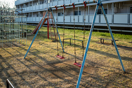 Empty swings and jungle gym in an old public housing playground in the evening
