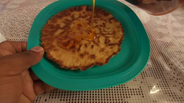Pouring Natural Honey over a Wheat Flatbread