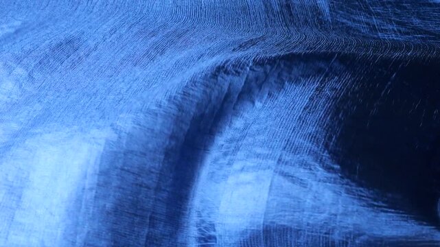 Blue natural silk fabric waving in the wind. Abstract background with soft organic waves and fluid motion. Minimalist pattern with shades of deep blue and azure. Elegant textile texture.
