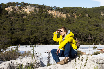 Naklejka premium Young woman in yellow jacket resting on a mountain ridge