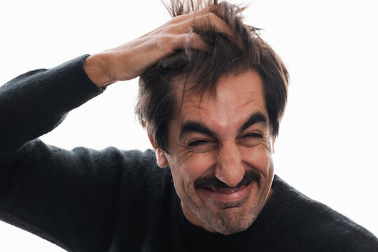 Man expresses joy while playfully tousling his hair in bright light