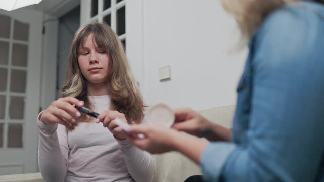 Teenage girl learning makeup application from mother