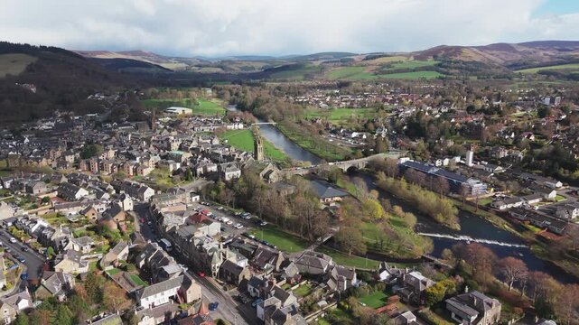 Cinematic drone flyover above the River Tweed flowing through the historic town of Peebles in the Scottish Borders landscape