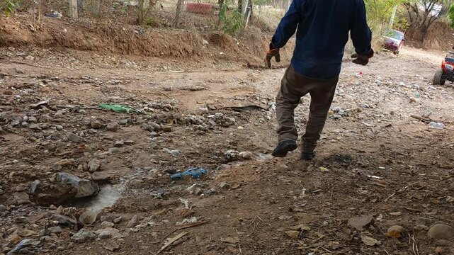 Man Lifting a Concrete Block in a Natural Ravine