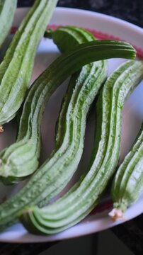 Fresh green Ridge Gourd or Turai placed on a white plate